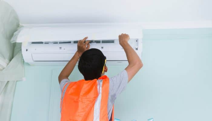 Homeowner performing a DIY AC reset by pressing the reset button