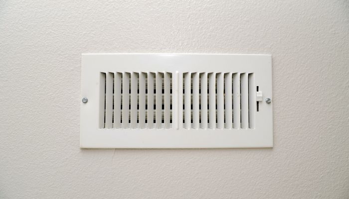 Wall air vent partially closed to control airflow in a home cooling system